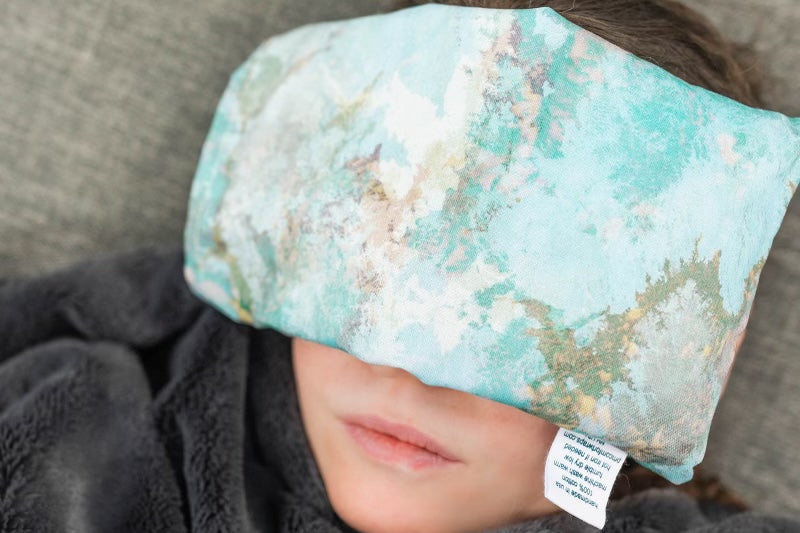 Person relaxing with a Parker Mountain Comfort Wraps Earth Views eye pillow resting over their closed eyes