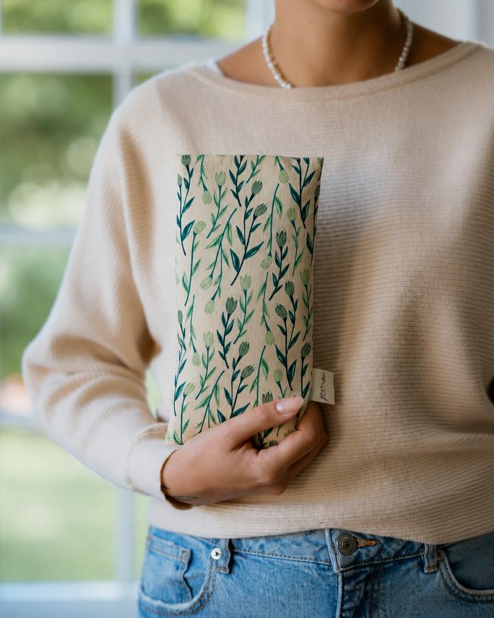 Seagrass weighted eye pillow with green botanical print held in hand