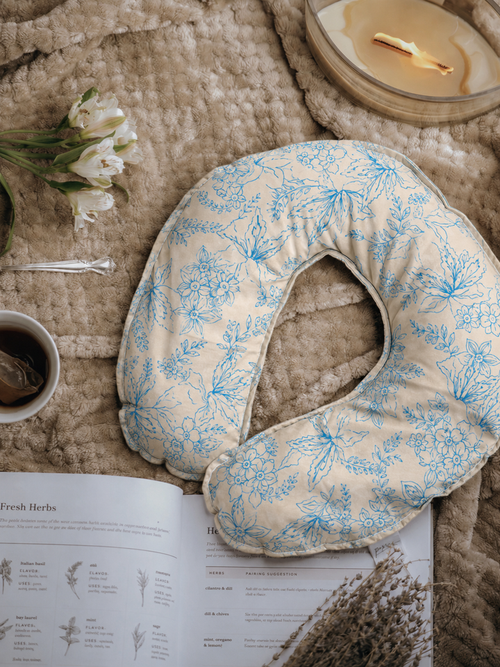 Periwinkle Cove weighted neck pillow with blue floral print flat lay with tea and candle