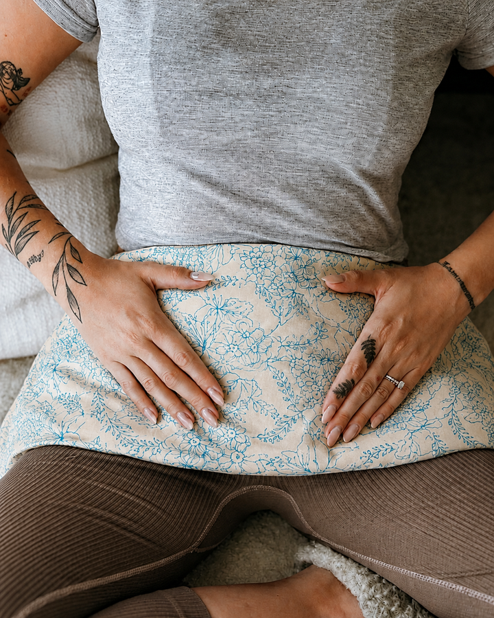 Periwinkle Cove weighted body wrap with blue floral print resting on lap for cramp relief